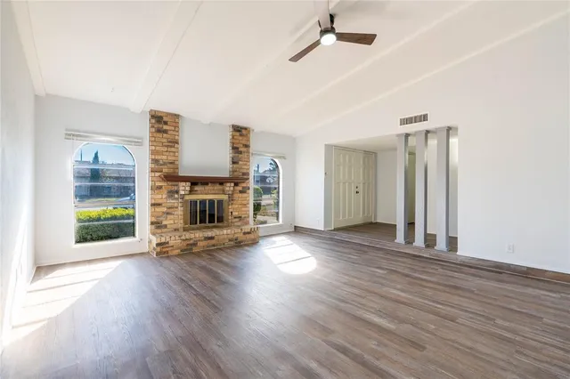 a view of a livingroom with wooden floor a ceiling fan and windows