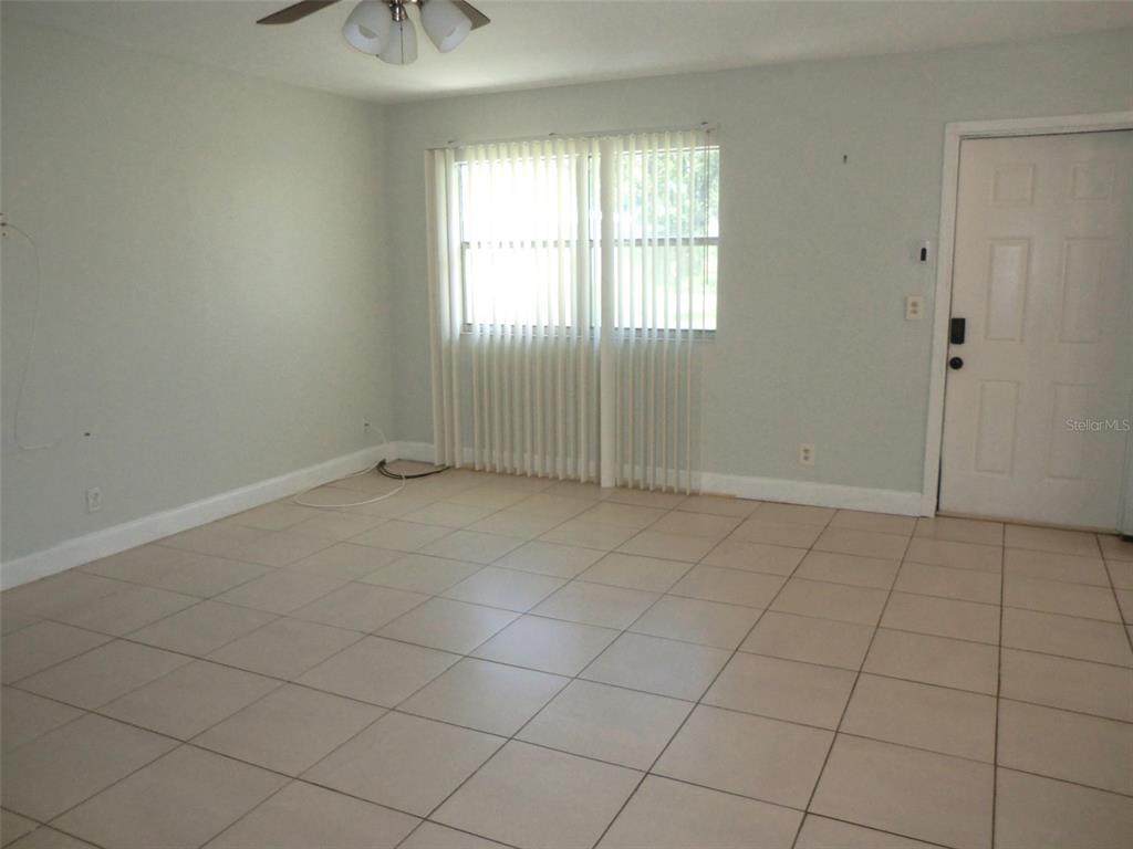 102 Cambridge Trail, Unit 229 Sun City Center, FL 33573 - Photo 3 of 18 an empty room with windows and chandelier fan