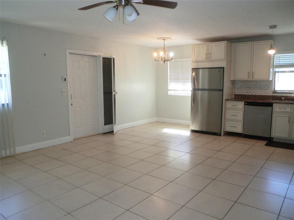 102 Cambridge Trail, Unit 229 Sun City Center, FL 33573 - Photo 5 of 18 an empty room with kitchen and chandelier fan