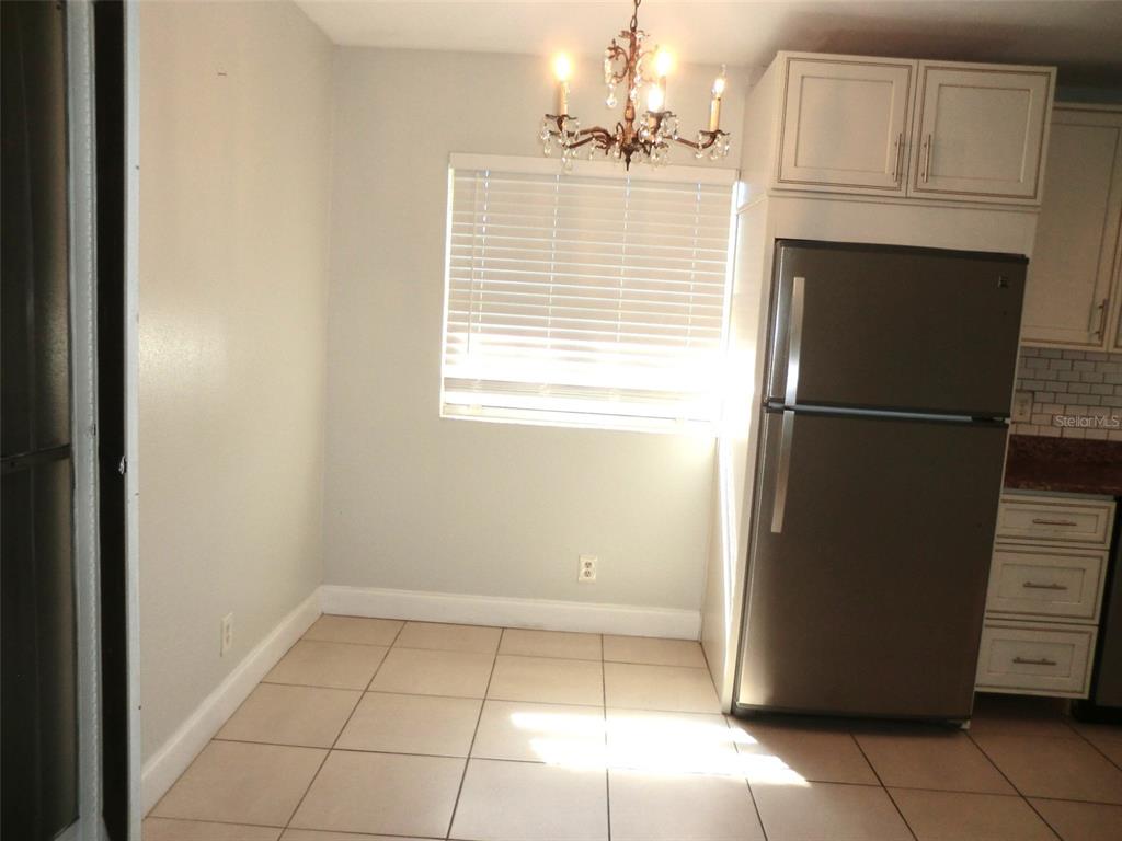 102 Cambridge Trail, Unit 229 Sun City Center, FL 33573 - Photo 7 of 18 a view of a refrigerator in kitchen and an empty room with wooden floor