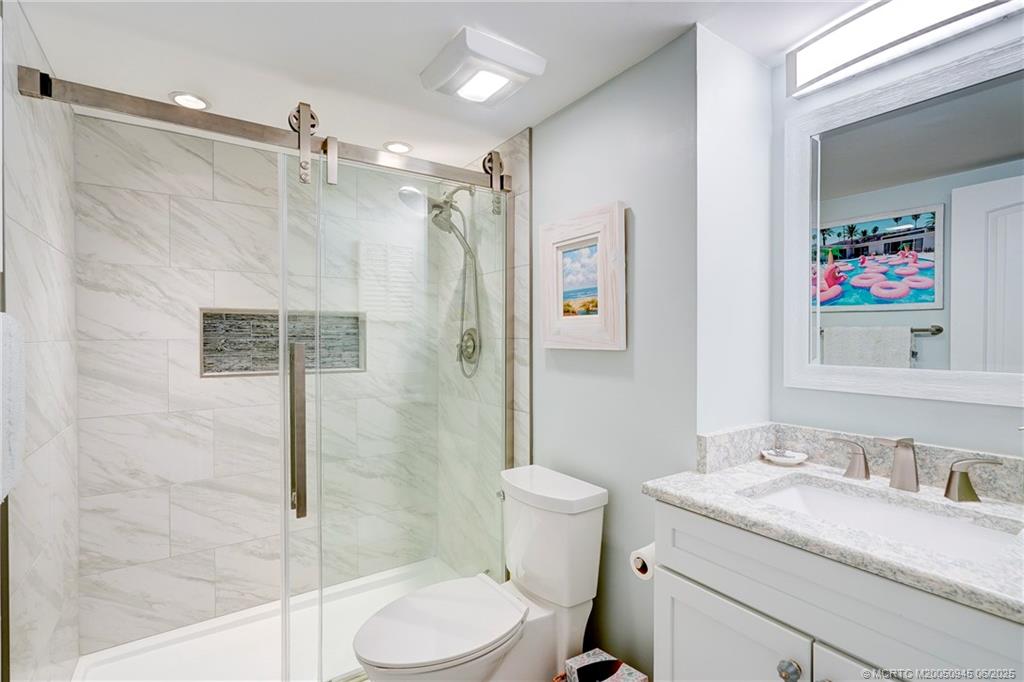 245 Northeast MacArthur Boulevard, Unit 11 Stuart, FL 34996 - Photo 20 of 47 a bathroom with a granite countertop sink toilet and shower