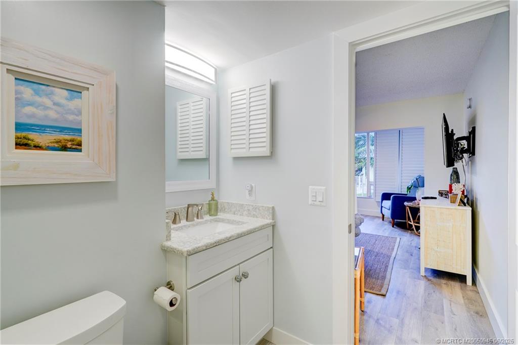 245 Northeast MacArthur Boulevard, Unit 11 Stuart, FL 34996 - Photo 21 of 47 a en suite bathroom with a granite countertop sink and a mirror