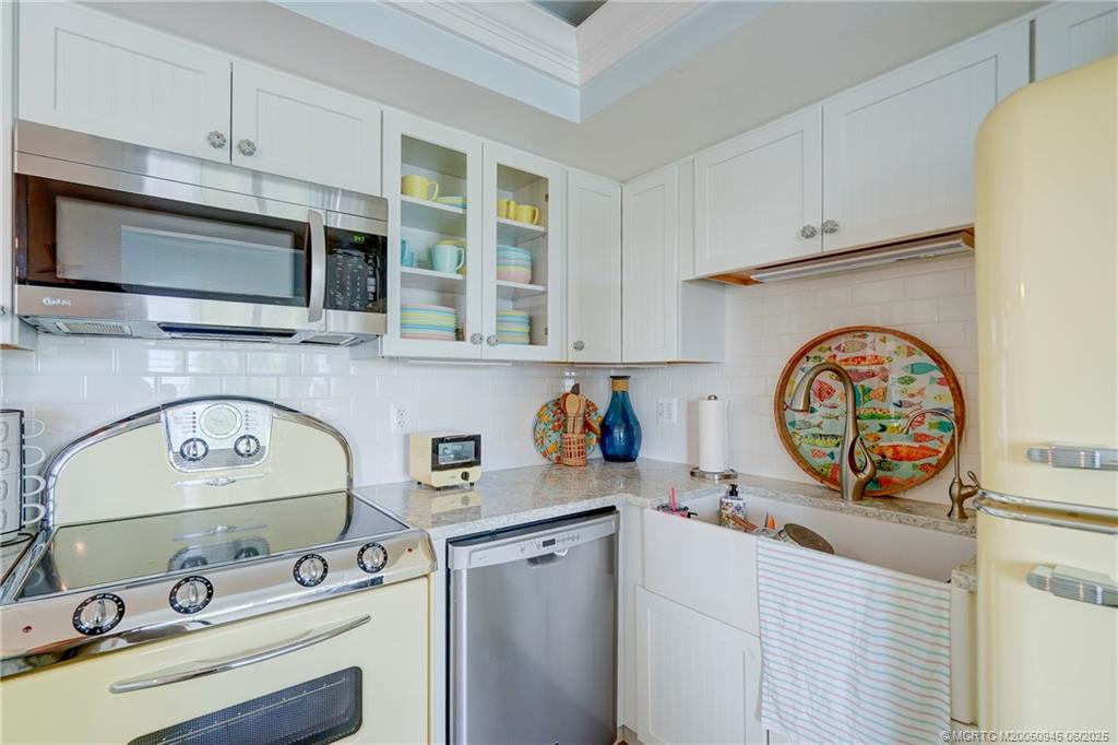 245 Northeast MacArthur Boulevard, Unit 11 Stuart, FL 34996 - Photo 33 of 47 a kitchen with stainless steel appliances a stove a microwave and cabinets