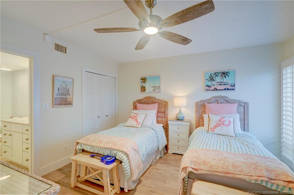 245 Northeast MacArthur Boulevard, Unit 11 Stuart, FL 34996 - Photo 8 of 47 a bedroom with two beds and a chandelier