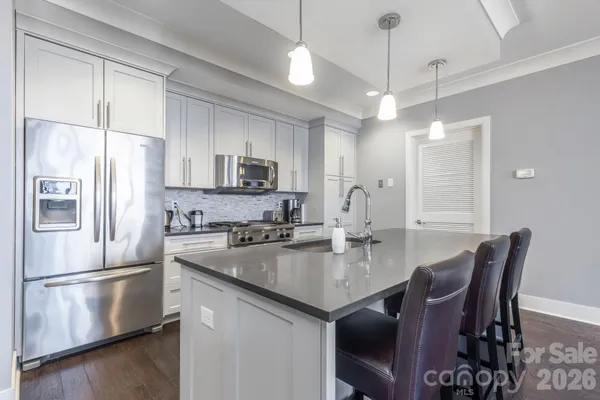 a kitchen with stainless steel appliances granite countertop a stove a refrigerator a sink a dining table and chairs