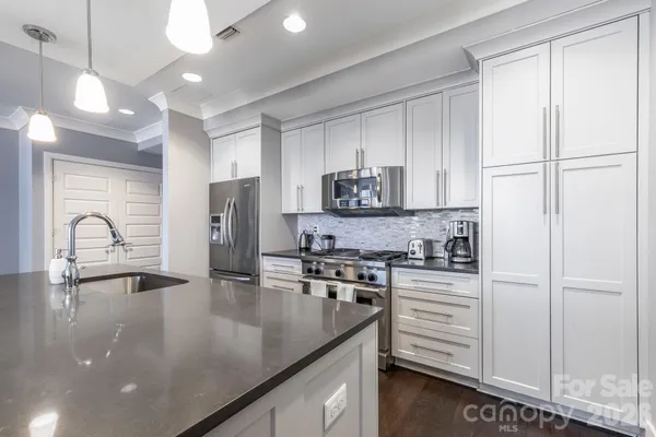 a kitchen with stainless steel appliances granite countertop a sink a stove and a refrigerator