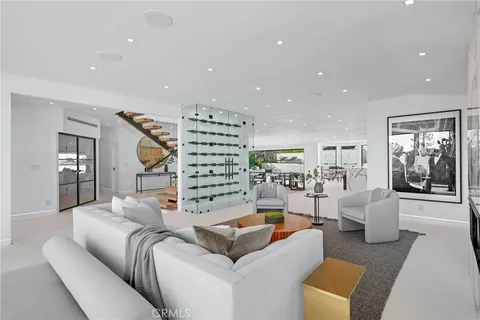 a living room with furniture a rug kitchen view and a large window