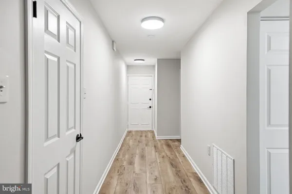 a view of a hallway with wooden floor and a bathroom