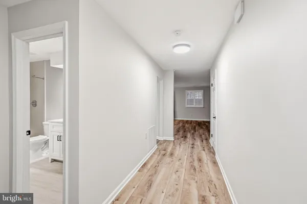 a view of a hallway with wooden floor and a bathroom