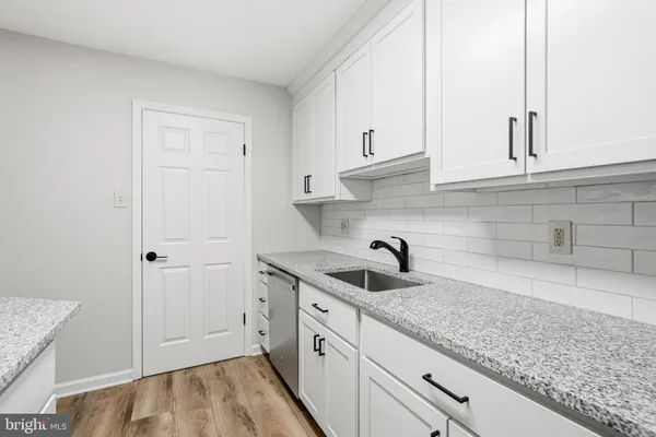 a kitchen with granite countertop white cabinets and a sink
