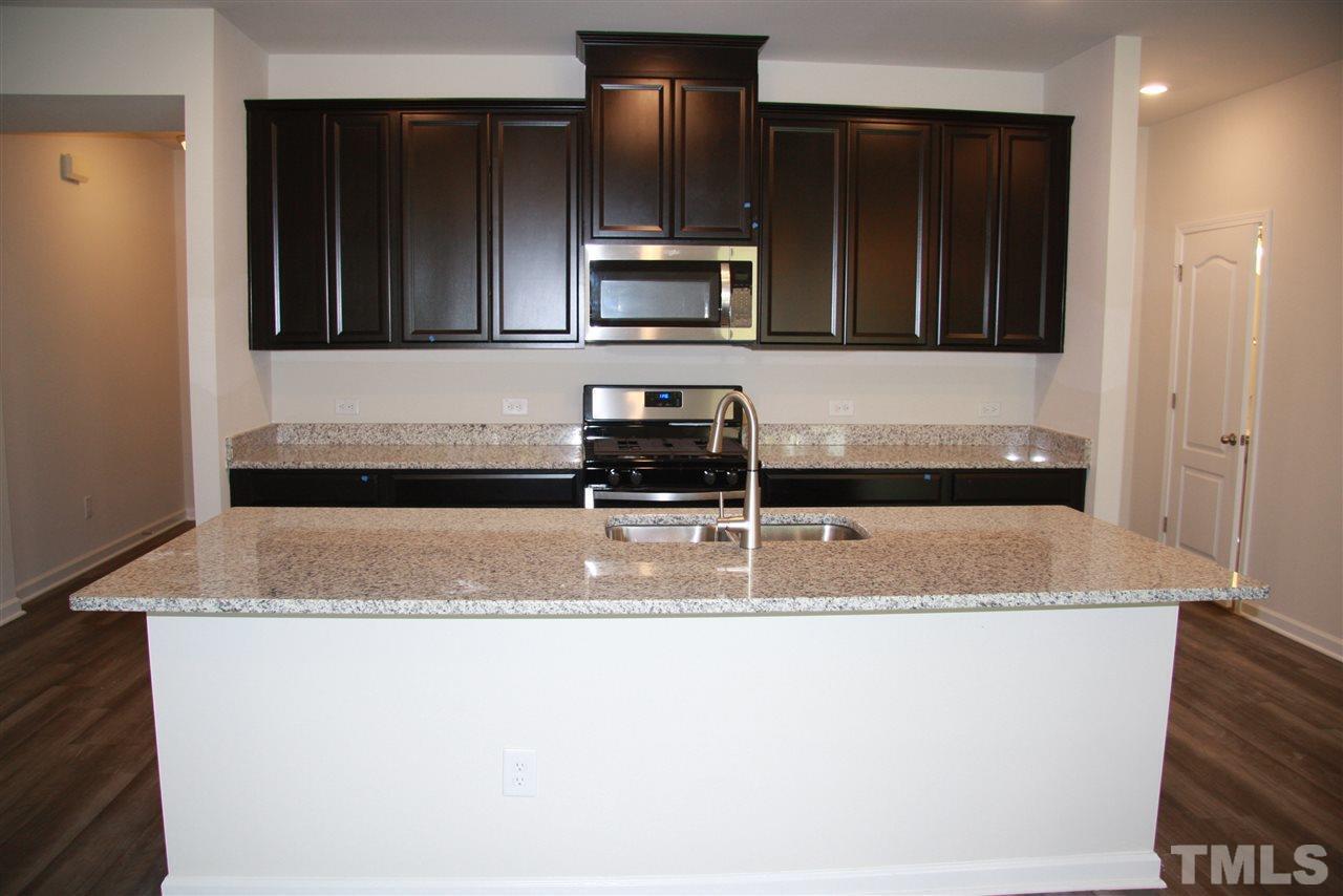 1154 Chestnut Bluff Apex, NC 27502 - Photo 6 of 26 a kitchen with granite countertop a sink and a stove top oven