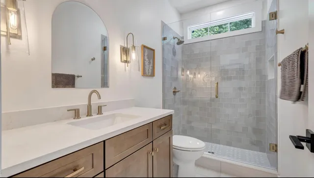 a bathroom with a sink a toilet a mirror and shower