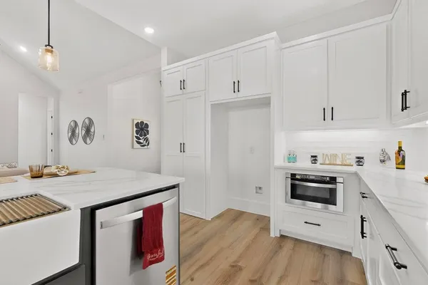 a kitchen with granite countertop a sink stove and white cabinets with wooden floor
