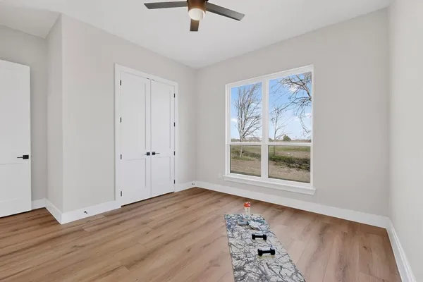 a view of an empty room with wooden floor and closet