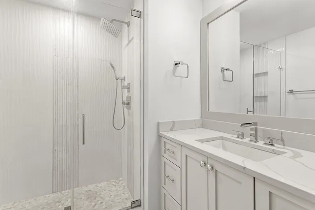 a bathroom with a sink vanity granite shower and a mirror