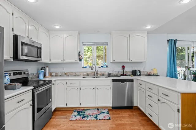 a kitchen with granite countertop white cabinets white stainless steel appliances with a sink and dishwasher