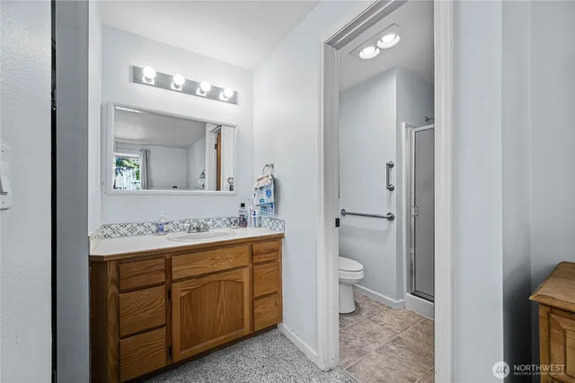 a bathroom with a toilet a sink a mirror and a shower