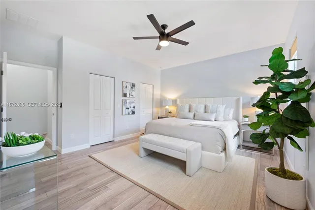 a bedroom with a potted plant and a ceiling fan