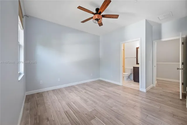 an empty room with wooden floor and a ceiling fan