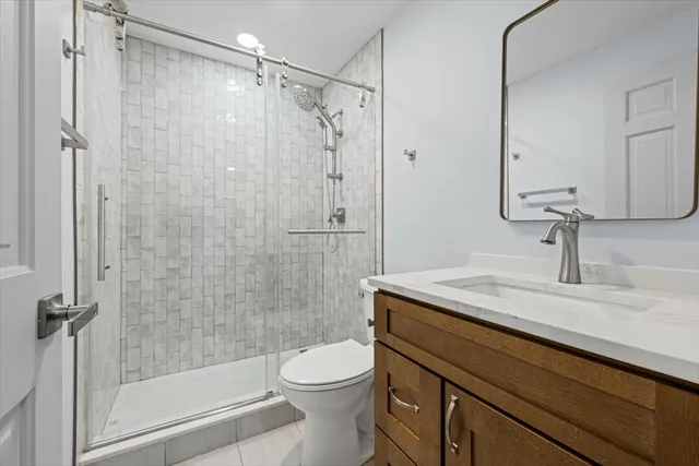 a bathroom with a granite countertop sink a toilet and shower