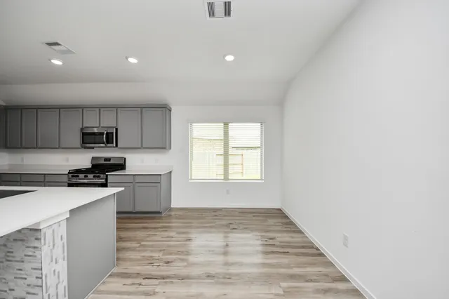 a kitchen with granite countertop a stove top oven sink and cabinets
