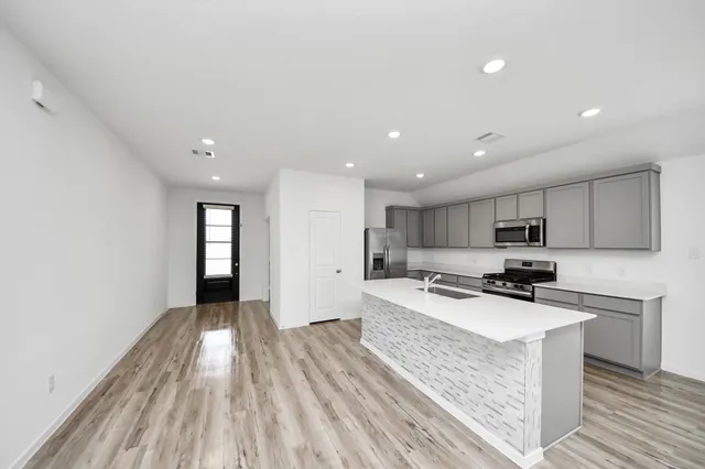 a kitchen with a sink a stove cabinets and a wooden floor