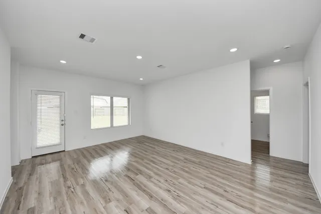 an empty room with wooden floor and windows