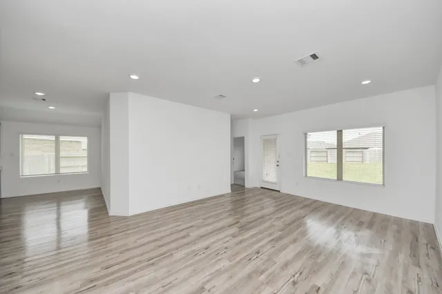 an empty room with wooden floor and windows