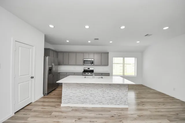 a large white kitchen with kitchen island a sink stainless steel appliances and cabinets