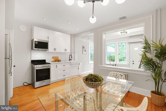 a kitchen with granite countertop a refrigerator a stove a dining table and chairs with wooden floor