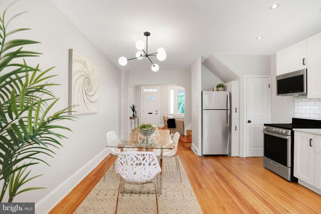 a kitchen with stainless steel appliances kitchen island granite countertop a refrigerator a stove a sink and white cabinets with wooden floor