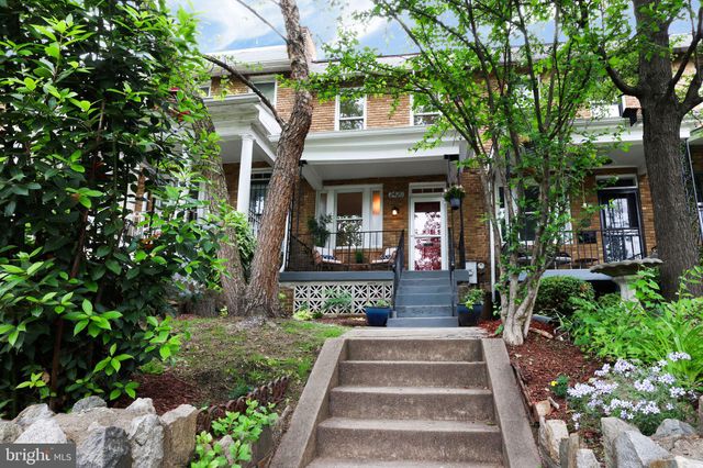 a front view of a house with a tree in front