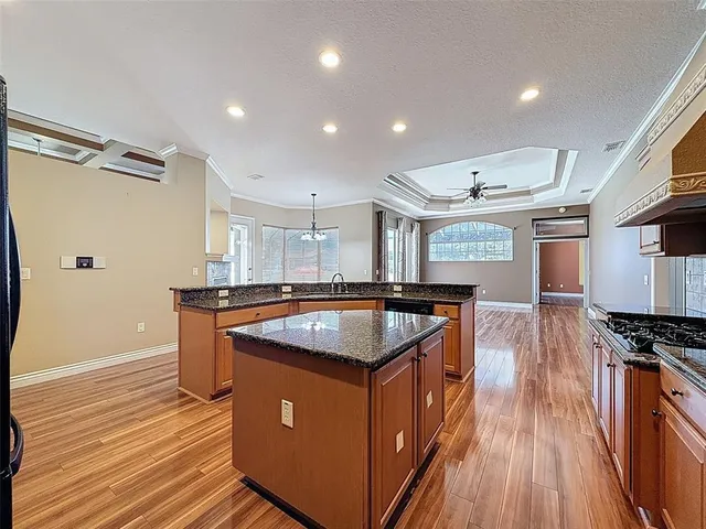 a kitchen with kitchen island stainless steel appliances a sink wooden floor and counter top space