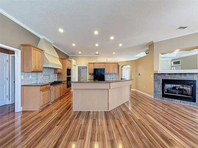 a large living room with stainless steel appliances granite countertop a couch and a fireplace