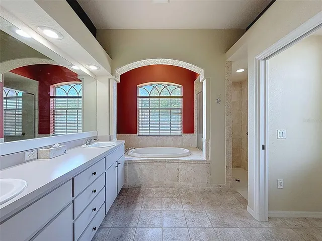 a spacious bathroom with a sink a mirror a bathtub and next to a window