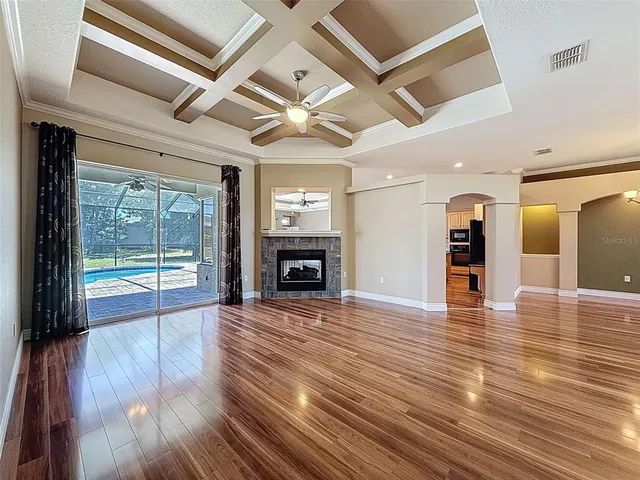 a view of an empty room with wooden floor and a fireplace