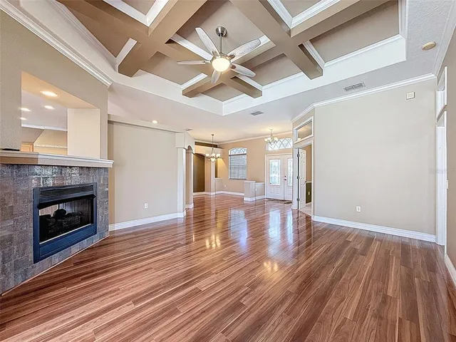 a view of an empty room with wooden floor fireplace and a window