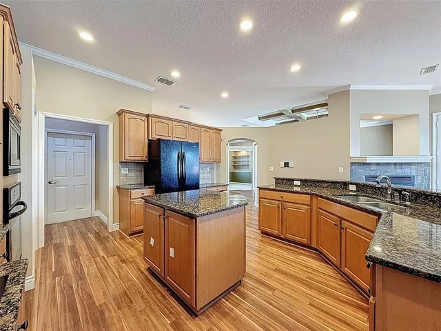 a kitchen with stainless steel appliances granite countertop a stove a sink and a refrigerator