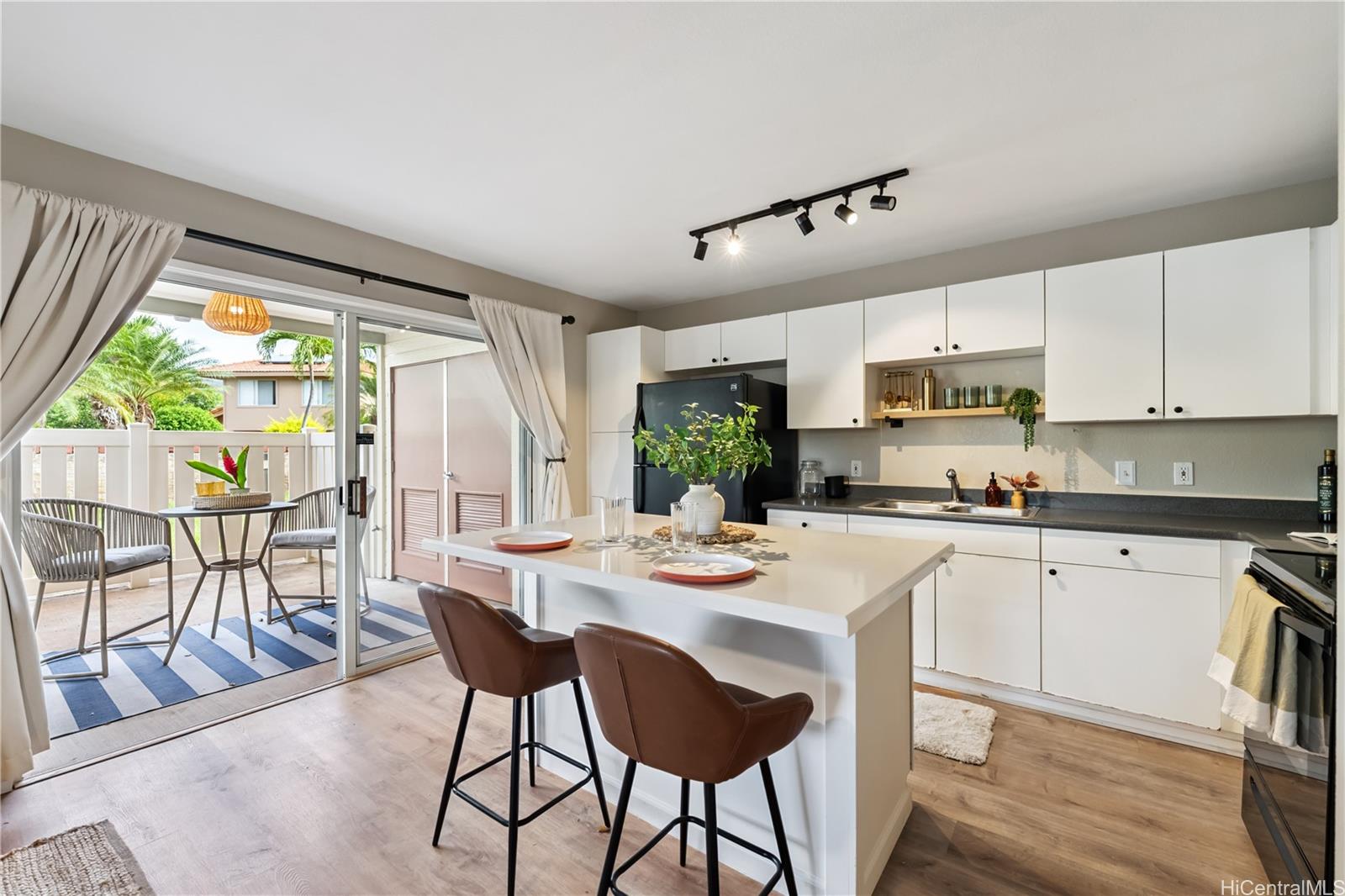 91-1097 Namahoe Street, Unit 4A Kapolei, HI 96707 - Photo 1 of 1 a kitchen with stainless steel appliances kitchen island granite countertop a stove a refrigerator a white table and chairs with wooden floor