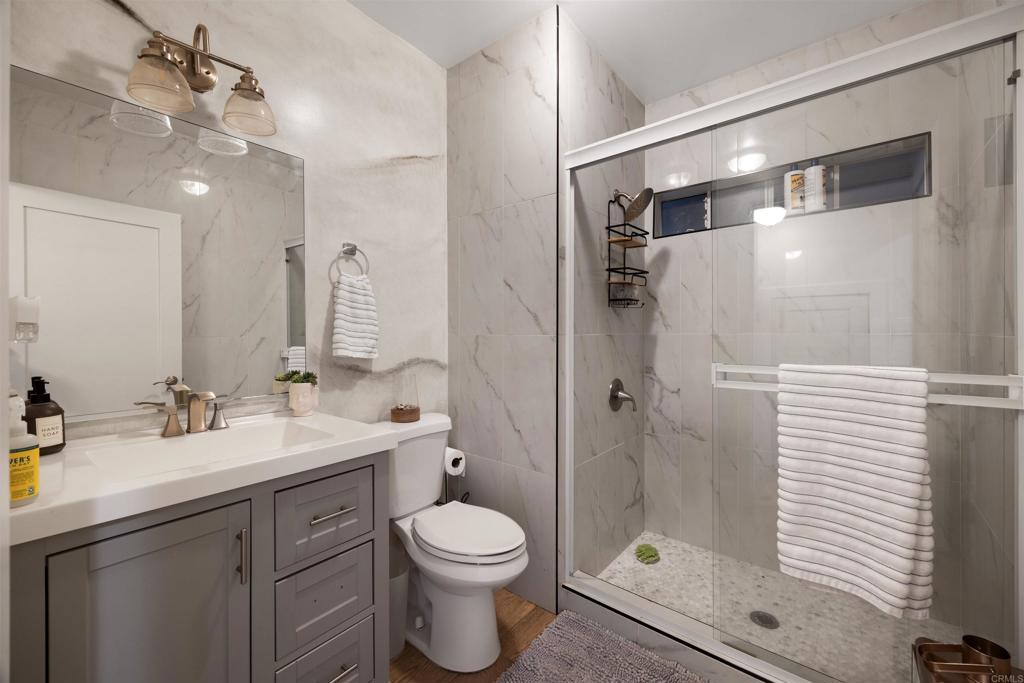 7965 4th Place Downey, CA 90241 - Photo 17 of 41 a bathroom with a toilet a sink a glass door a shower a mirror and vanity