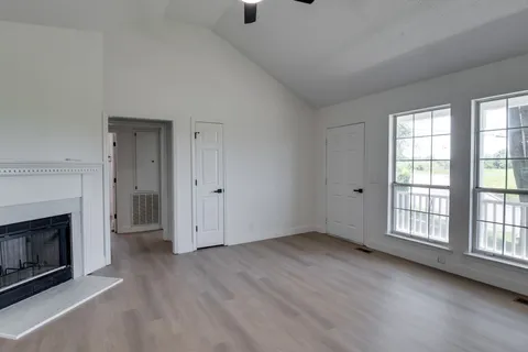 an empty room with windows and fireplace