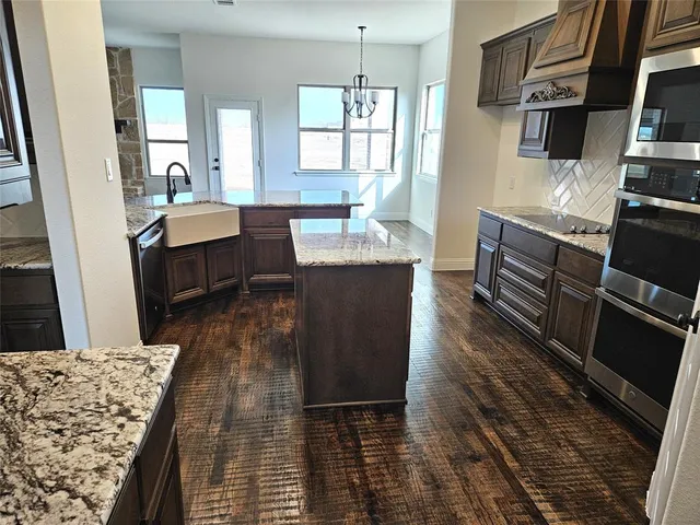 a kitchen with stainless steel appliances granite countertop a refrigerator a stove a sink dishwasher and wooden floor