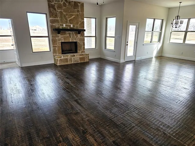 an empty room with wooden floor fireplace and windows