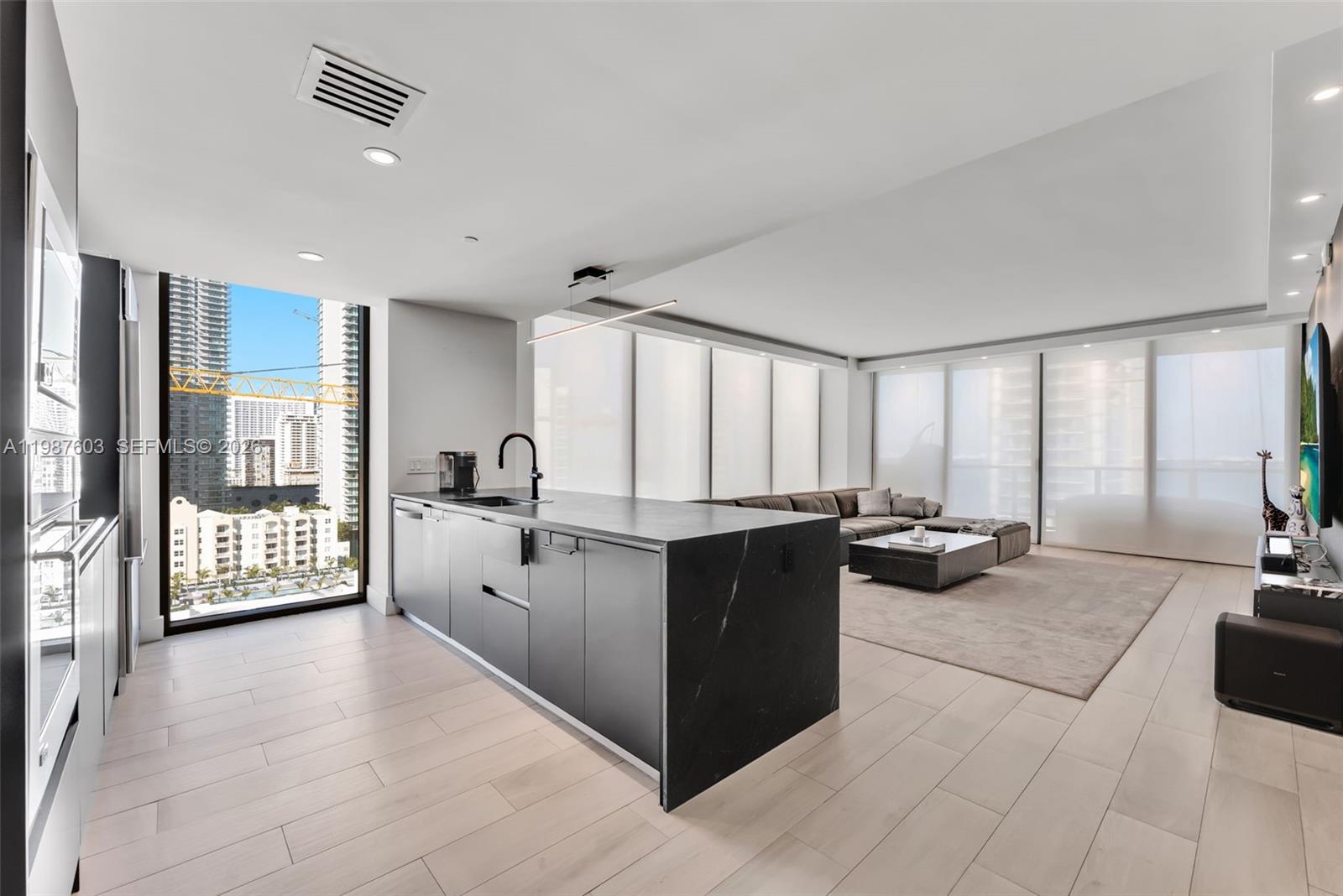 460 Northeast 28th Street, Unit 1601 Miami, FL 33137 - Photo 10 of 41 a large white kitchen with stainless steel appliances granite countertop a large counter top a couch and a view of living room