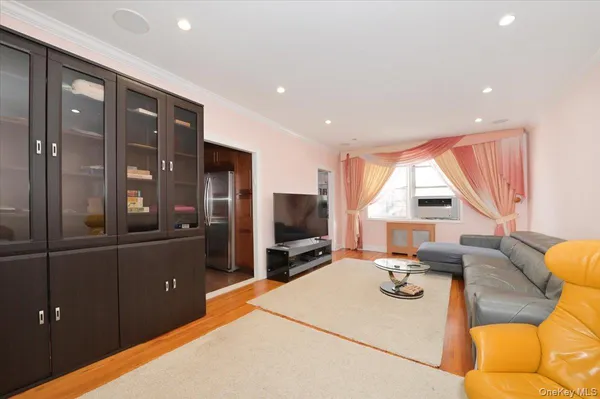 a living room with furniture a flat screen tv and a refrigerator
