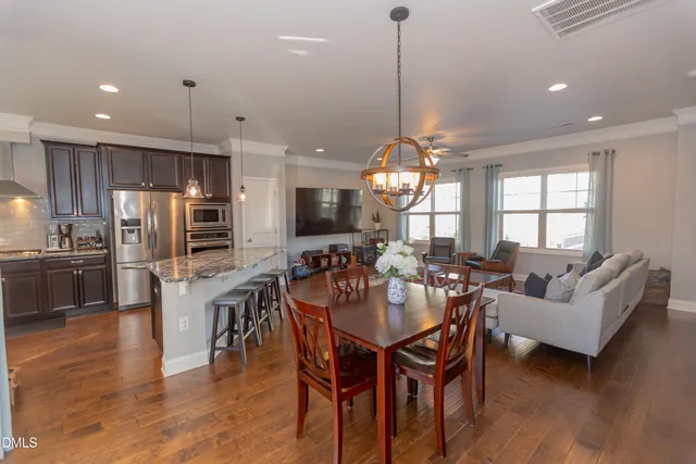 a view of a dining room and livingroom with furniture wooden floor a chandelier