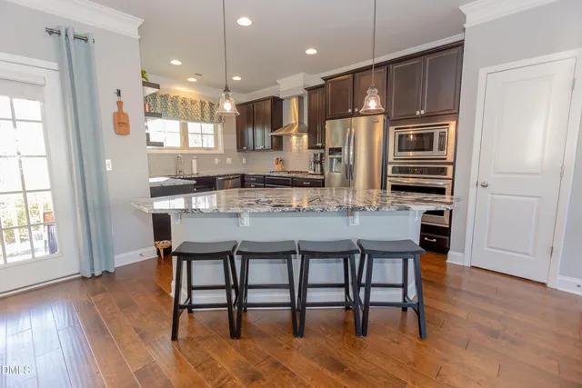 a kitchen with stainless steel appliances a dining table chairs stove and refrigerator