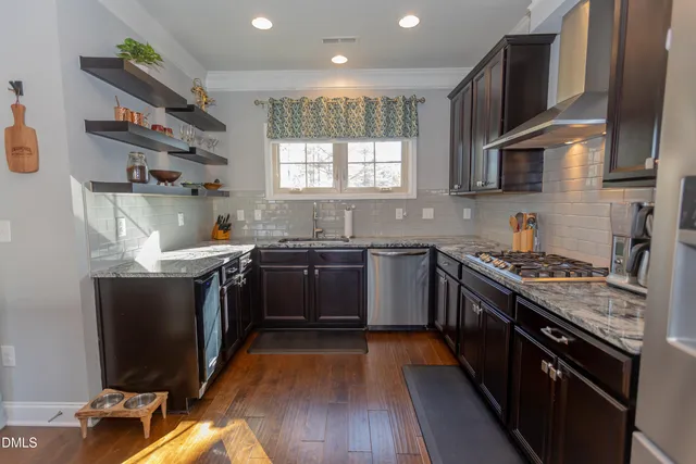 a kitchen with stainless steel appliances granite countertop wooden cabinets a sink dishwasher a stove and a refrigerator