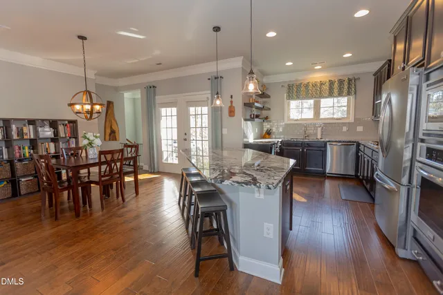 a view of a dining room and livingroom with furniture wooden floor a chandelier