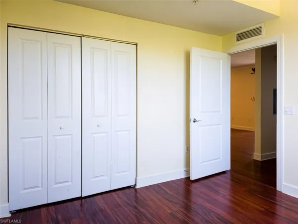 a view of an empty room with closet and wooden floor